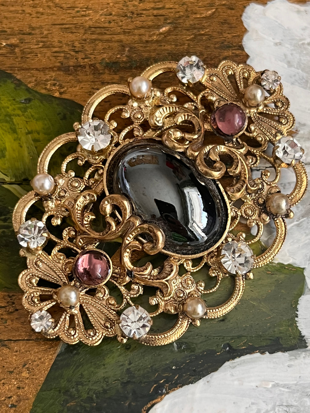Vintage gold baroque-style brooch with black cabochon and rhinestones on gold-colored filigree