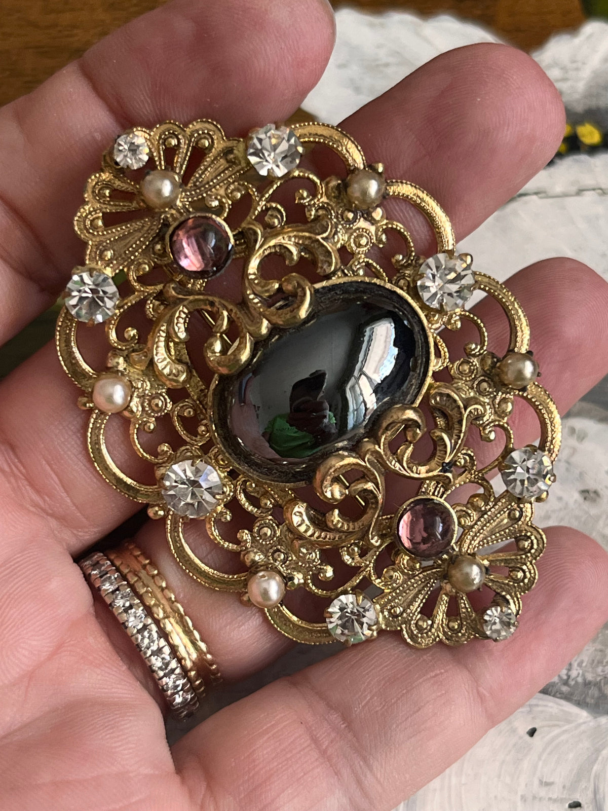 Vintage gold baroque-style brooch with black cabochon and rhinestones on gold-colored filigree