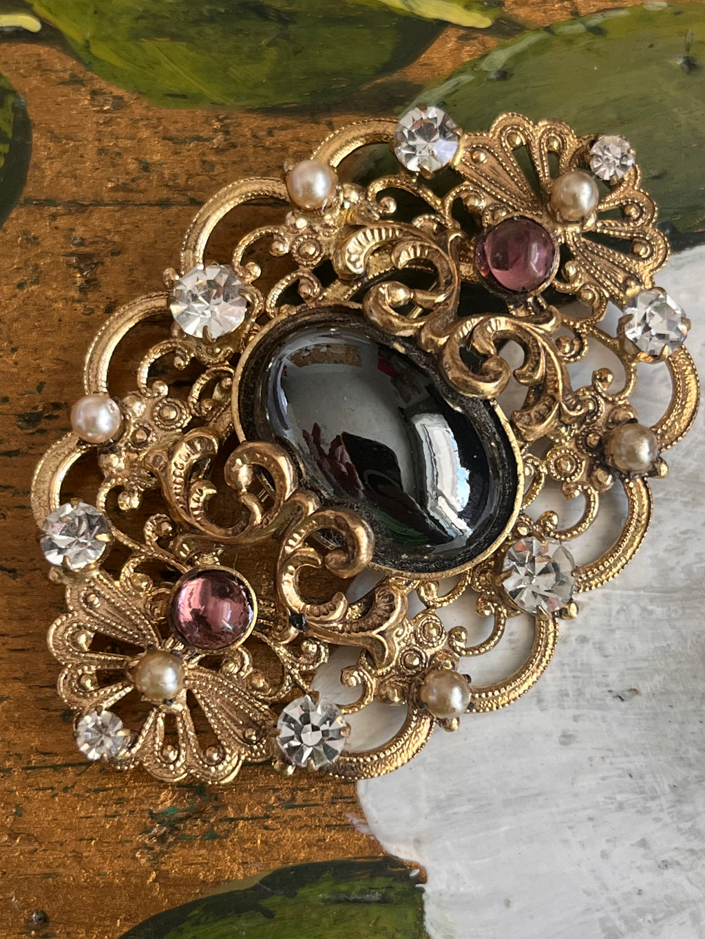 Vintage gold baroque-style brooch with black cabochon and rhinestones on gold-colored filigree