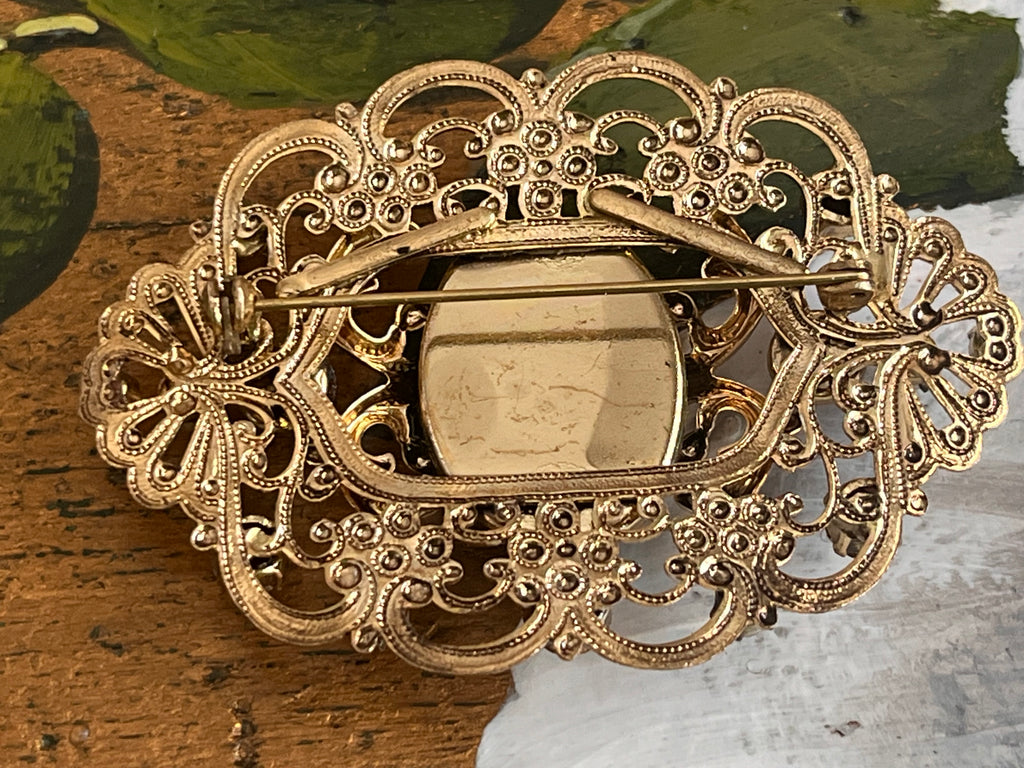 Vintage gold baroque-style brooch with black cabochon and rhinestones on gold-colored filigree