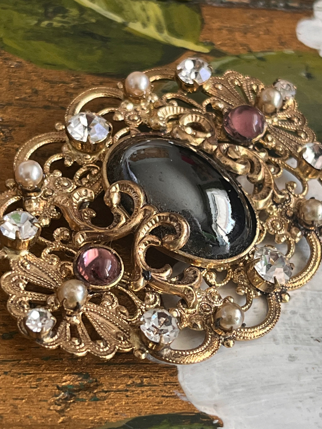 Vintage gold baroque-style brooch with black cabochon and rhinestones on gold-colored filigree
