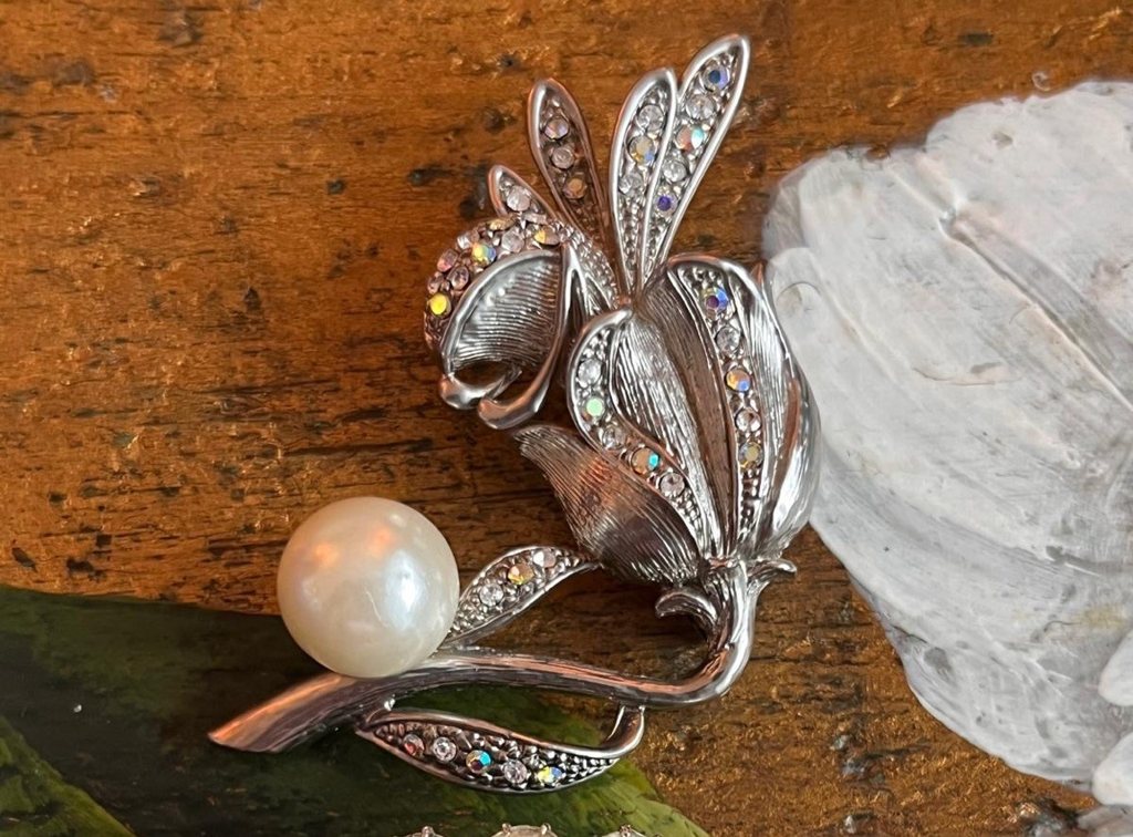 Spilla argentata a fiore con dettagli luminosi e grande perla chiara decorativa