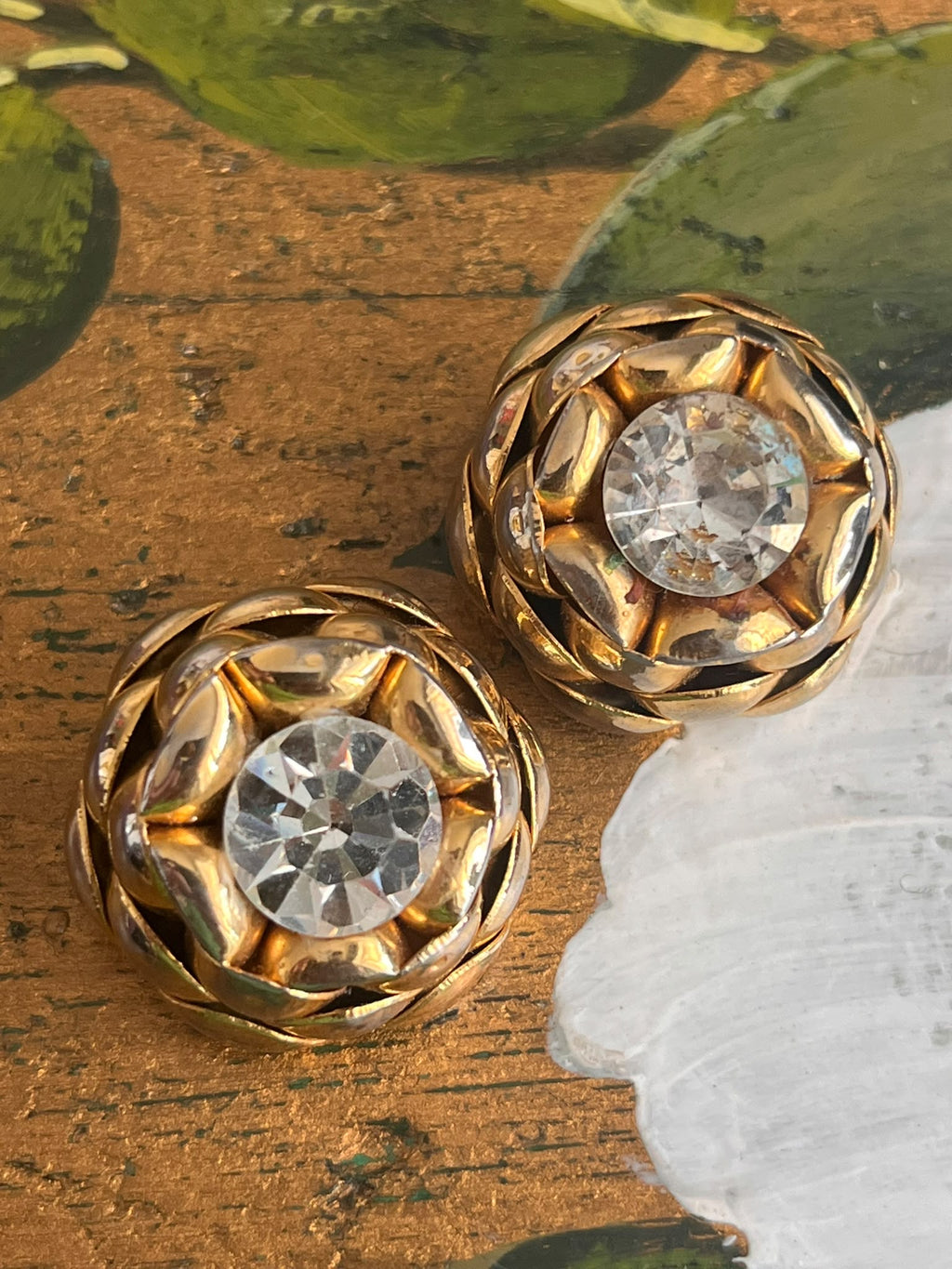 Orecchini vintage con strass trasparenti e finitura dorata, coppia fotografata su superficie decorata